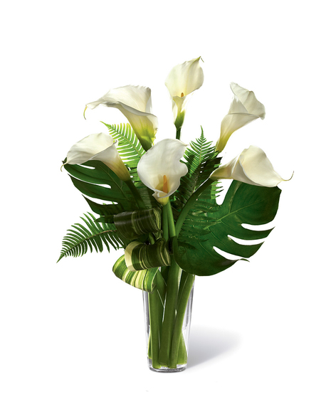 Bouquet of white calla lilies and greenery in a clear glass vase