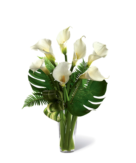 Bouquet of white calla lilies and greenery in a clear glass vase