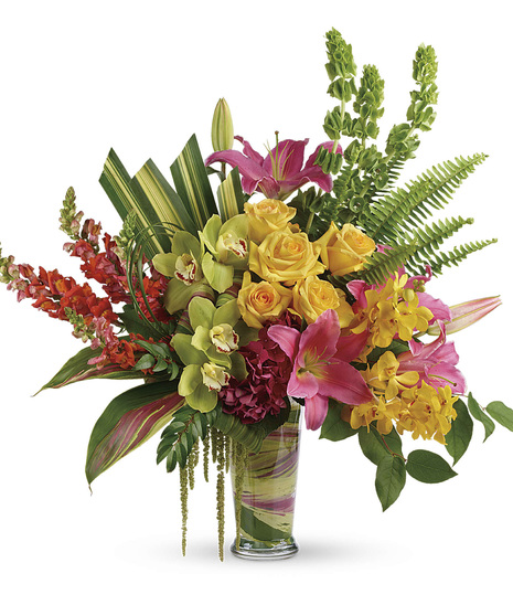 Bright roses, orchids, lilies and more in a leaf-lined glass vase